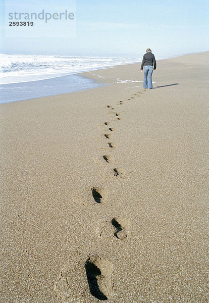 Eine Frau  die am Strand spazieren geht.