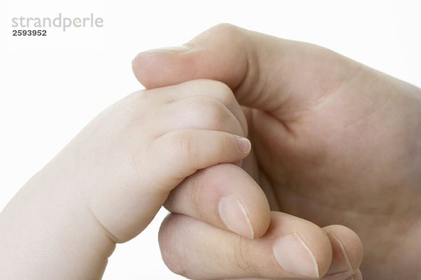 Die Hand eines Babys hält den Finger eines Erwachsenen.