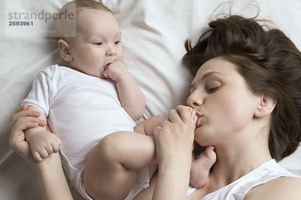 Eine Mutter  die den Fuß ihres Babys küsst.