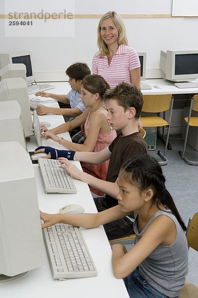 Ein Lehrer und vier Kinder vor der Pubertät in einem Computerlabor