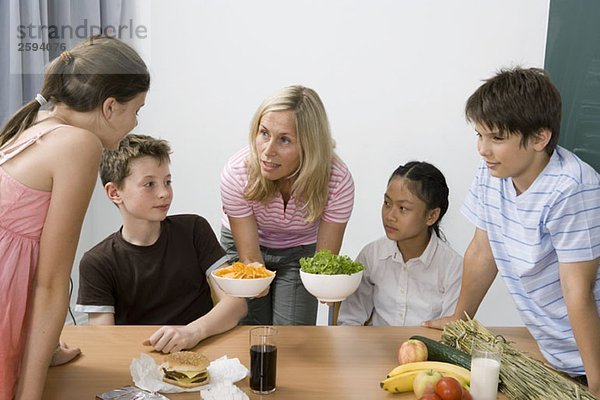 Ein Lehrer und vier Schüler  die etwas über Ernährung lernen.