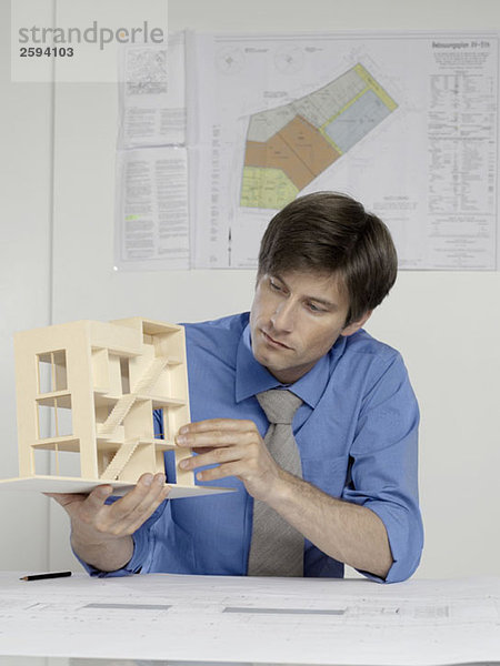 Ein Architekt  der ein Architekturmodell untersucht.