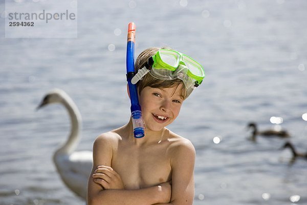 Ein kleiner Junge mit einer Tauchermaske vor einem See
