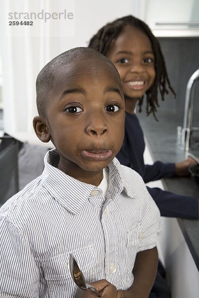 Ein kleiner Junge macht ein lustiges Gesicht  während sein Bruder hinter ihm lächelt.