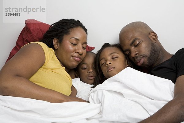 Eine vierköpfige Familie  die zusammen im Bett schläft.