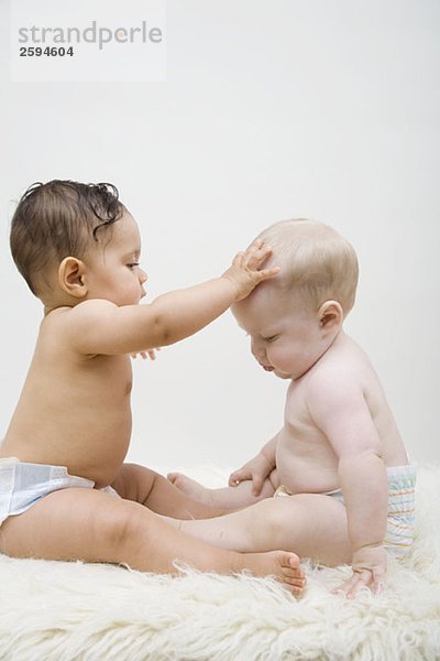 Zwei Babys sitzen von Angesicht zu Angesicht