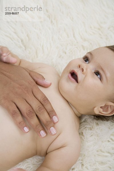 Eine menschliche Hand  die ein Baby tröstet.