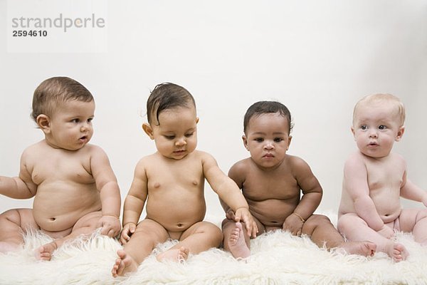 Vier Babys sitzend in einer Reihe