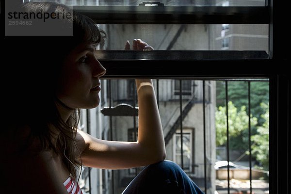 Eine lateinamerikanische Frau sitzt auf einem Fensterbrett.