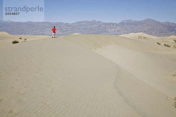 Eine Person  die entlang einer Sanddüne geht  Death Valley  Kalifornien  USA