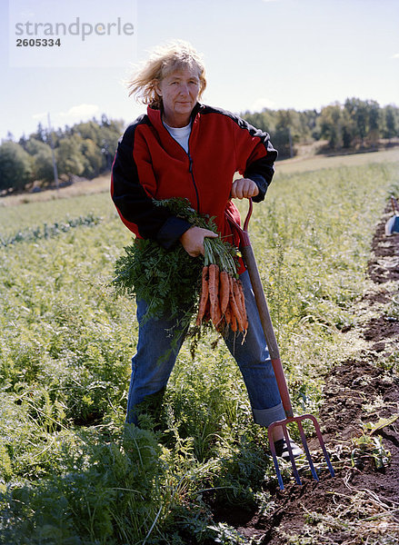 Eine Frau hält ökologische Karotten Aloppe Schweden