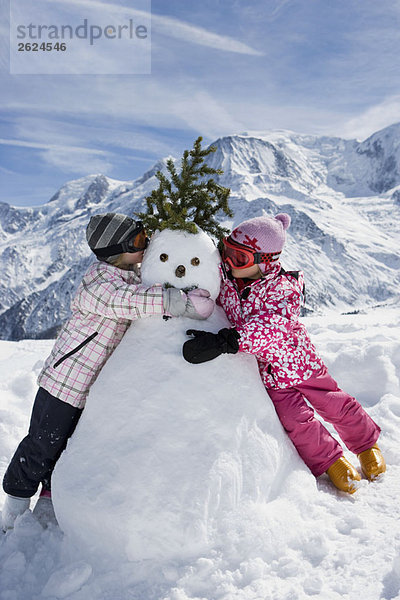 Zwei Mädchen mit einem Schneemann