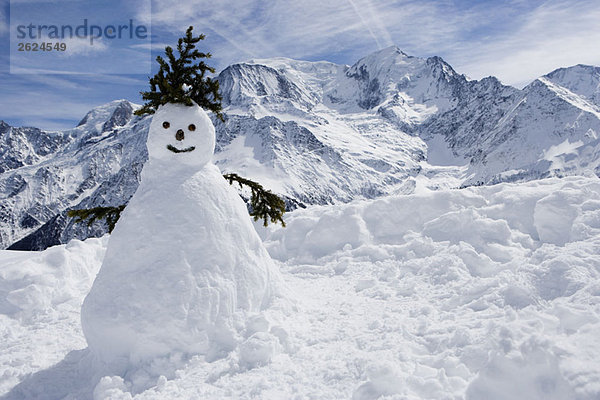 Ein Schneemann mit Bergen dahinter