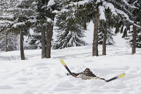 Frau im Schnee liegend mit Skiern