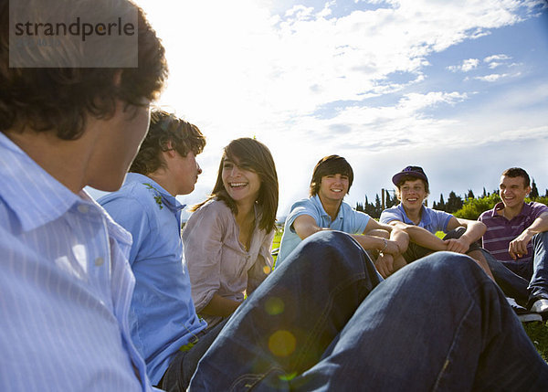 Teenagergruppe auf Rasen sitzend  redend