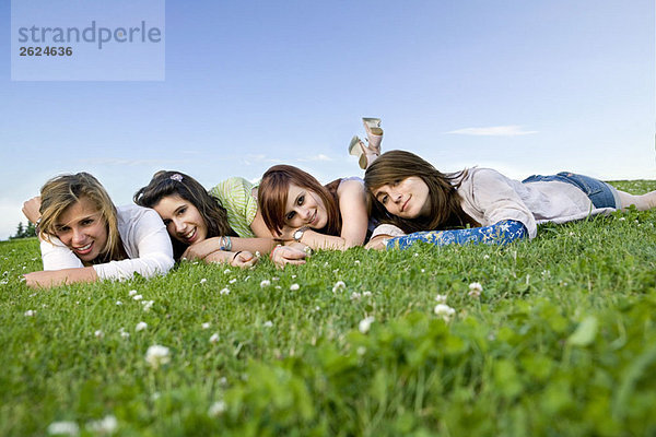 Porträt von vier Teenagern auf Gras liegend