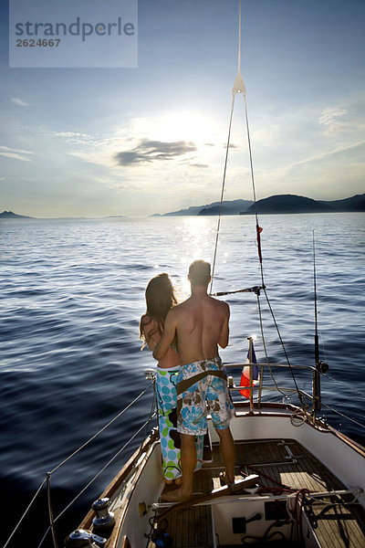 Paar beobachtet Sonnenuntergang auf einem Segelboot