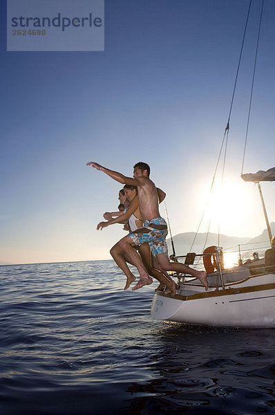 Junge Leute  die vom Segelboot springen