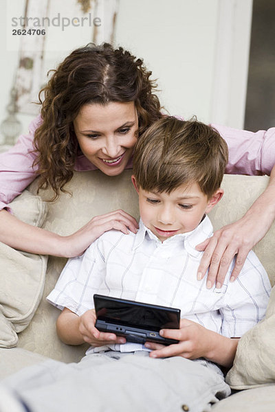 Frau schaut ihrem Sohn beim Videospielen zu.