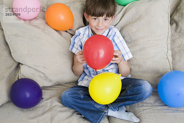 Kleiner Junge mit vielen Luftballons