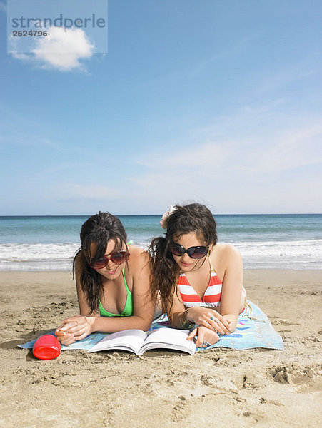 Zwei junge Frauen  die sich ein Buch teilen