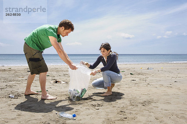 Junges Paar sammelt Müll am Strand