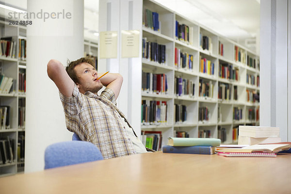 Junger Mann  der in der Bibliothek arbeitet