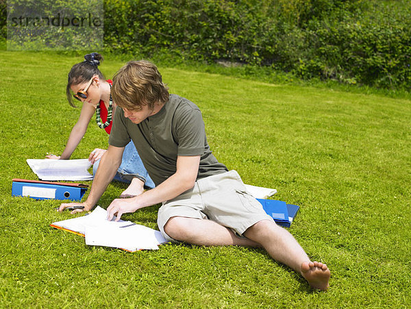 Zwei junge Leute studieren auf dem Rasen