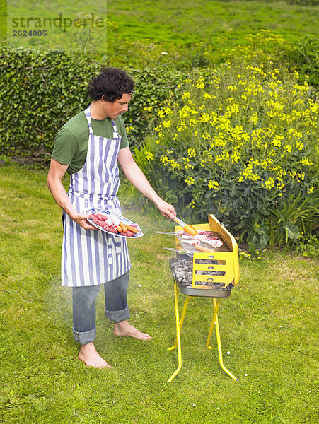 Junger Mann beim Grillen von Fleisch