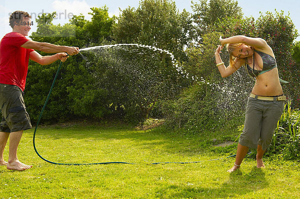 Mann Spritzfrau mit Gartenschlauch