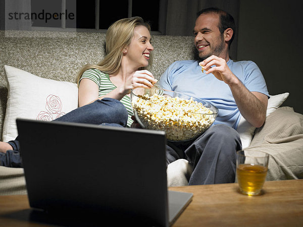 Junges Paar teilt sich Popcorn auf der Couch