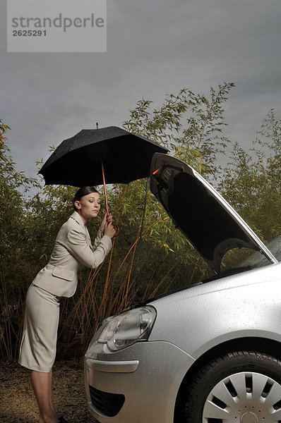 Frau schaut auf den Motor ihres Autos