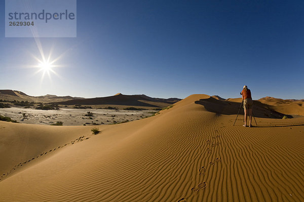 Afrika  Namibia  Fotograf in der Namib Wüste  Rückansicht
