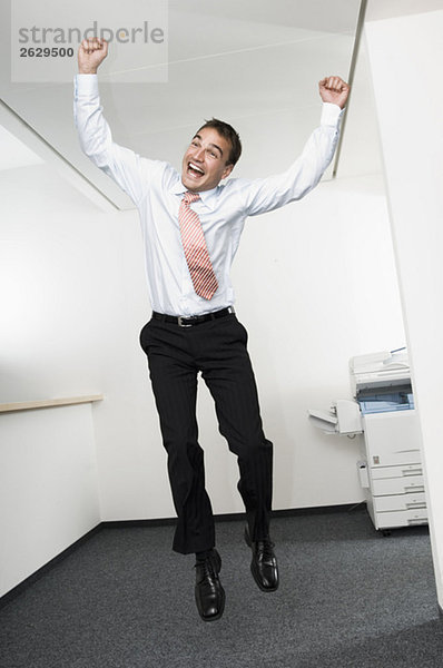 Geschäftsmann  der im Büro in die Luft springt  jubelnd