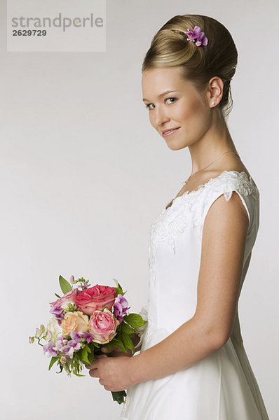 Junge Braut mit Brautstrauß  Seitenansicht