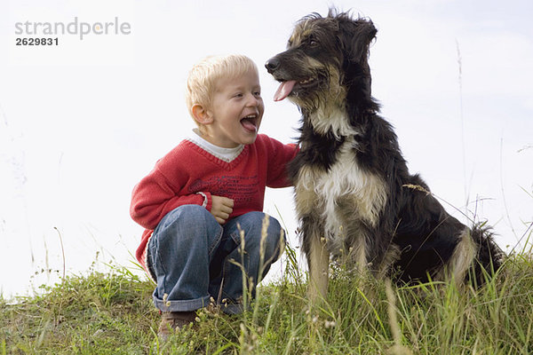 Kleiner Junge (3-4) spielt mit Hund