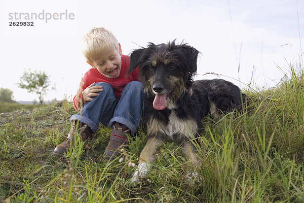 Kleiner Junge (3-4) spielt mit Hund