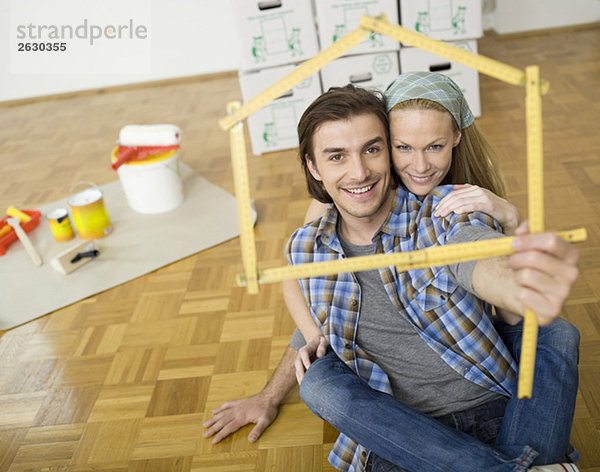 Junges Paar macht Hausform mit Zollstock  Portrait