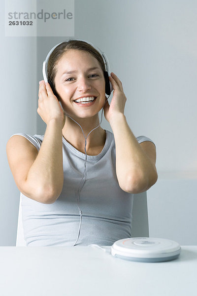 Frau hört tragbaren CD-Player  lächelt in die Kamera