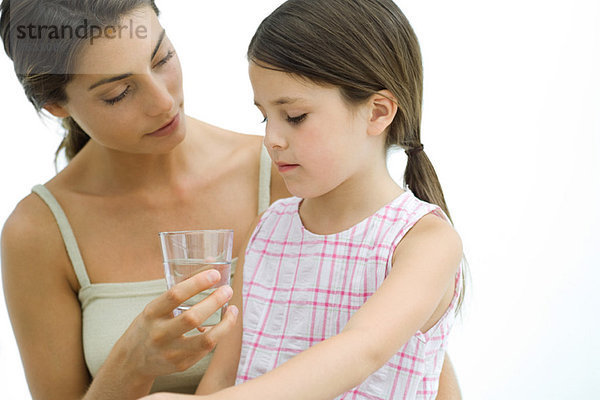 Mutter bietet der Tochter ein Glas Wasser an.