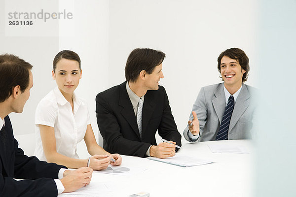 Geschäftspartner sitzen am Konferenztisch  schauen einander an  lächeln