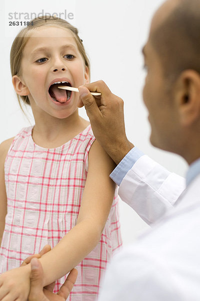 Arzt untersucht den Rachen eines Mädchens mit einem Zungenspatel