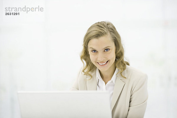 Professionelle Frau mit Laptop  lächelnd vor der Kamera