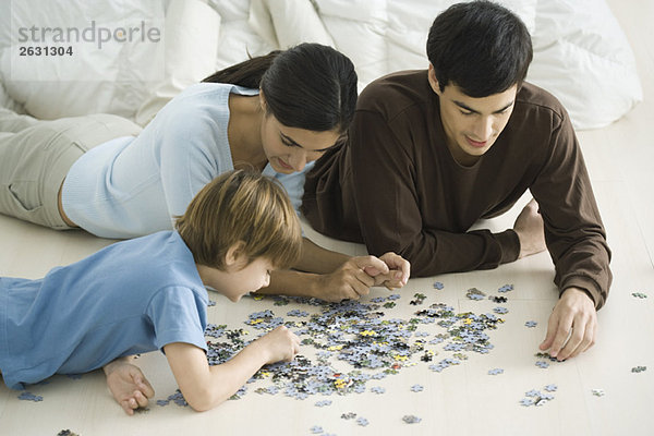 Familie auf dem Boden liegend  Puzzle zusammensetzend