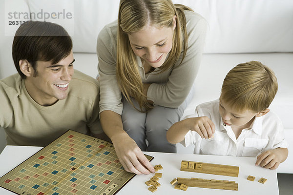 Familie spielt Brettspiel zusammen  Mutter arrangiert Spielsteine