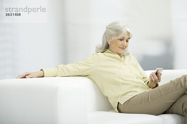 Seniorenfrau hört MP3-Player  sitzt auf der Couch