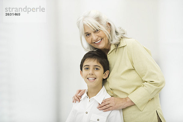 Großmutter steht hinter Enkel  beide lächelnd vor der Kamera  Porträt