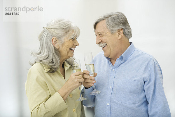 Seniorenpaar mit Champagnerflöten  die sich gegenseitig anlächeln