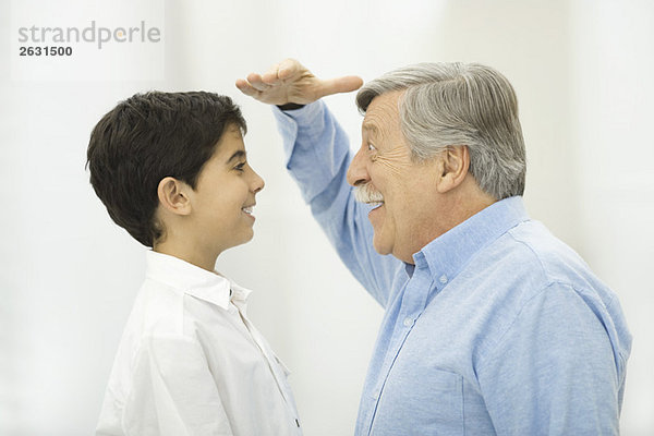 Großvater vergleicht Höhe mit Enkel  lächelt sich an.