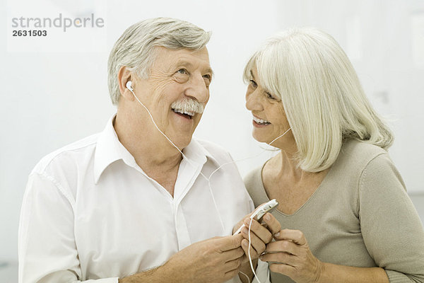 Seniorenpaar beim gemeinsamen Hören des MP3-Players
